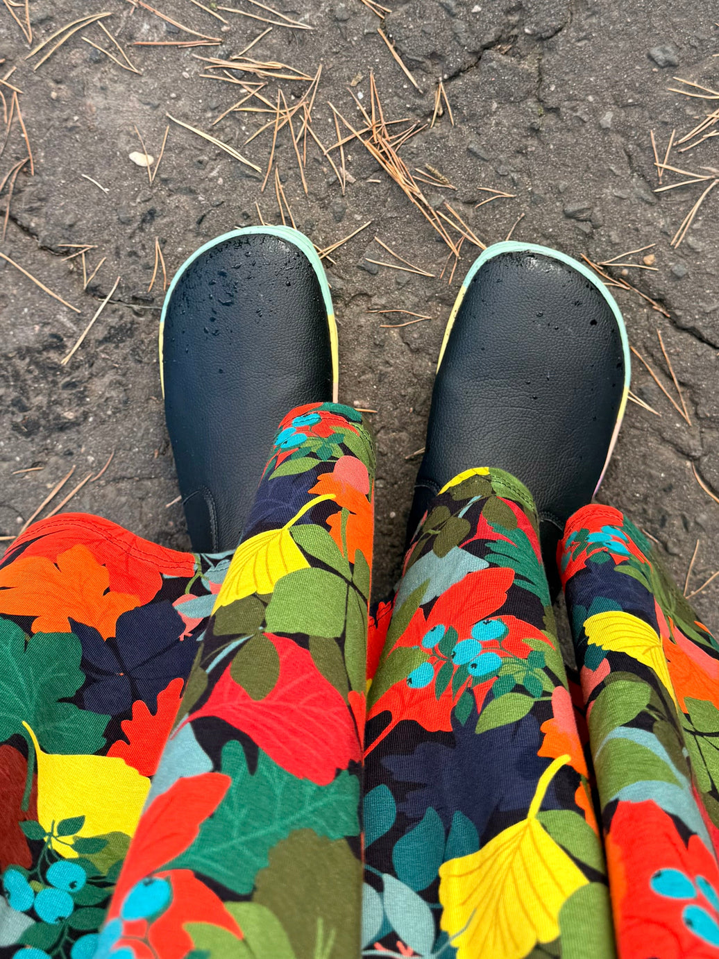 Black PaperKrane barefoot boots with colourful soles worn on feet outdoors, showing the roomy foot-shaped toe box