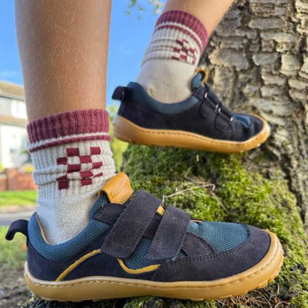 Child wearing barefoot shoes climbing a tree
