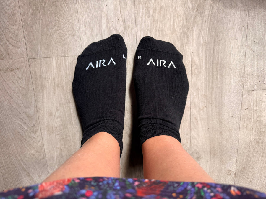 AIRA Basics black anatomical socks with white AIRA branding and L R toe markers worn on feet