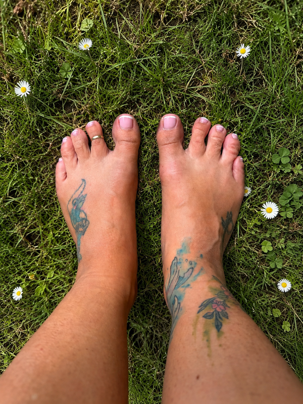 Bare feet on grass with daisies showing natural foot health