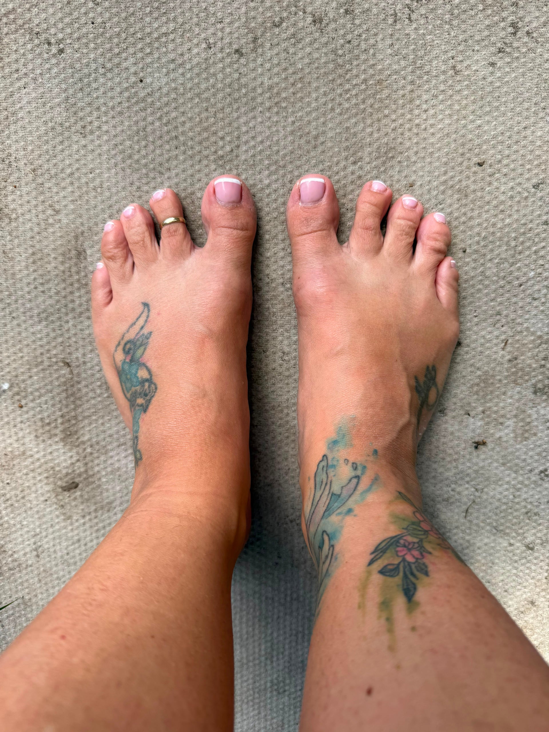 Bare feet with French manicure and toe ring on a textured surface, ready for measuring for barefoot shoes