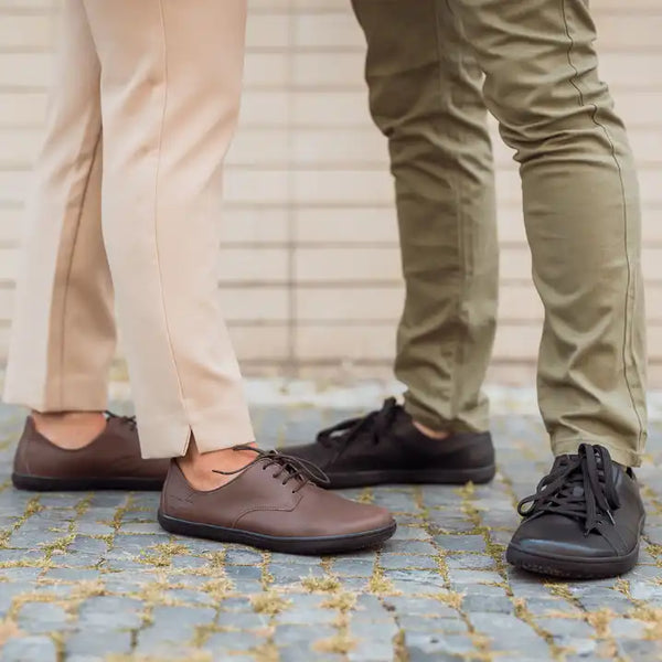 Men's and women's barefoot office shoes side by side on cobblestone
