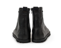 A pair of black leather tikki langs boots shown from the back, featuring side zippers and rugged black soles, set against a plain white background.